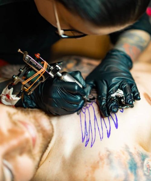 proceso salon tatuajes chica tatuadora relleno tatuaje proceso rellenar tatuaje cuerpo primer plano manos (1)